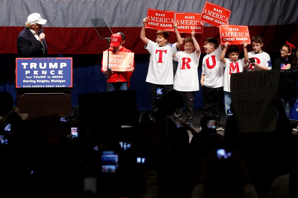 Donald Trump divide o palco com crianças vestindo camisetas formando o nome do candidato republicano à Casa Branca (FOTO: REUTERS/Carlo Allegri)