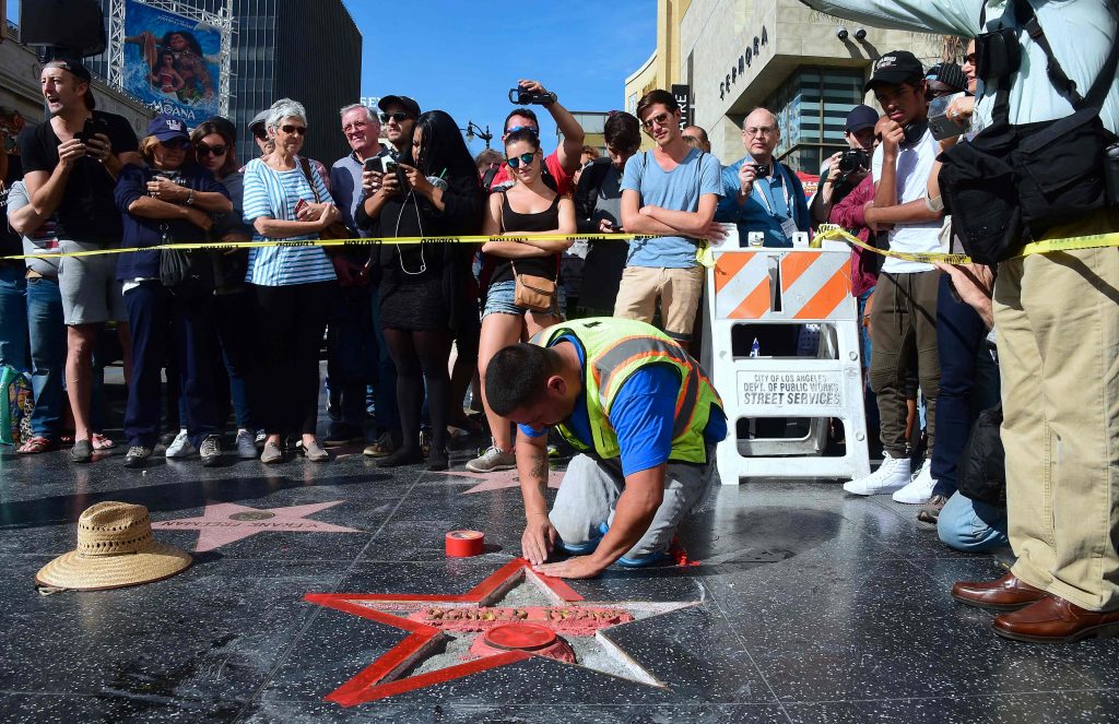 (FILES) This file photo taken on October 26, 2016 shows a crowd as it gathers to watch as Donald Trump's vandalized Star along the Hollywood Walk of Fame is repaired before being replaced on October 26, 2016 in Hollywood, California. A man who admitted to defacing Donald Trump's star on the Hollywood Walk of Fame in protest at the Republican presidential candidate's treatment of women was arrested on October 27, 2016, police said. James Otis had planned to hold a news conference in the early morning at the site of Trump's star and then surrender to police, but he was arrested beforehand. Otis, who had his misdeed filmed on Wednesday, said he initially wanted to remove the star and auction it in New York on Election Day. / AFP PHOTO / Frederic J. BROWN