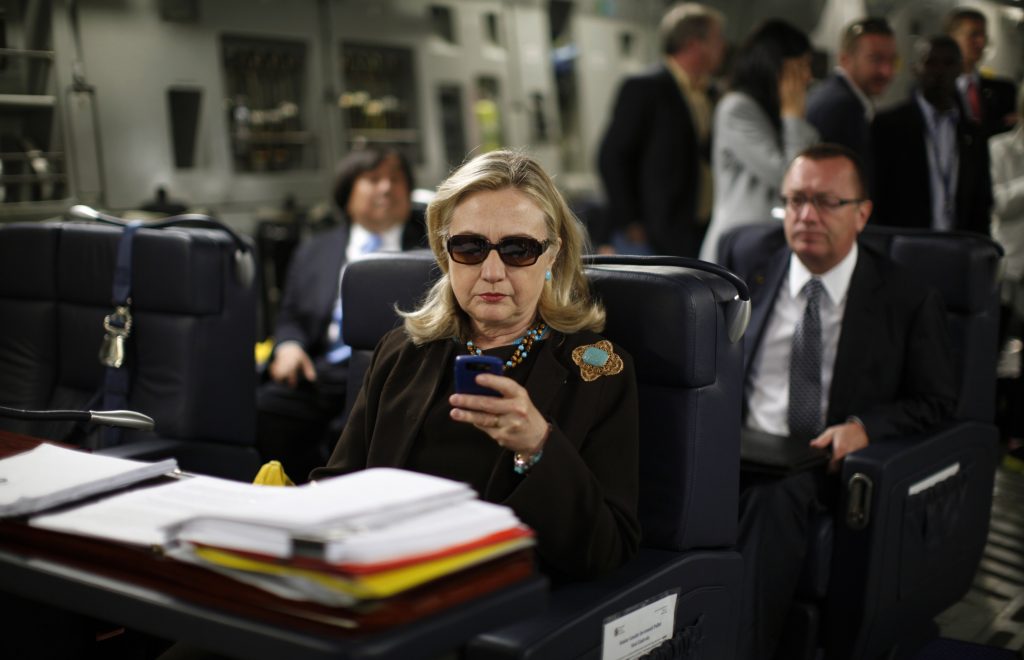Hillary usa seu celular dentro de um avião militar C-17 sobre o Mar Mediterrâneo quando era secretária de Estado, em 2011 (FOTO: AP Photo/Kevin Lamarque)