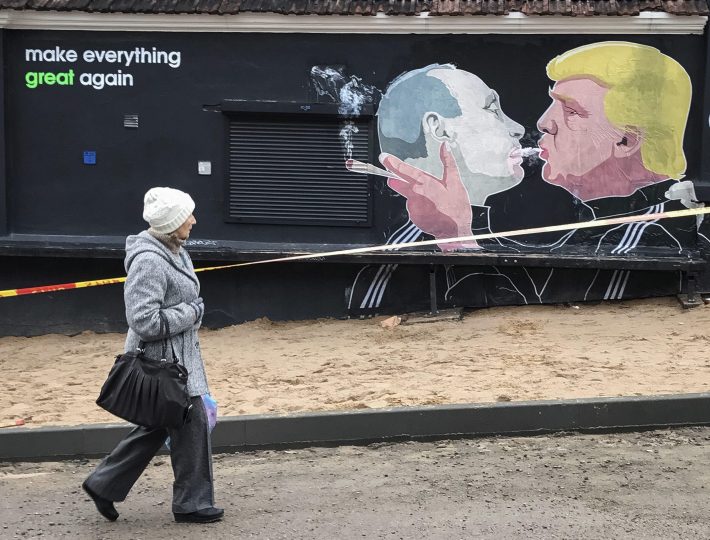 PIL02 VILNIUS (LITUANIA) 21/11/2016.- Una mujer pasa por delante de un grafiti que representa al presidente electo estadounidense, Donald Trump (d), y al presidente ruso, Vladímir Putin, mientras comparten el humo de un cigarro, en la pared de un restaurante en Vilnius, Lituania, el 20 de noviembre de 2016. EFE/Roman Pilipey