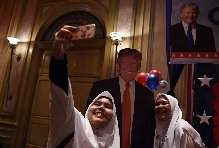Muçulmanas em Kuala Lampur, Malásia, tiram selfie com poster de Donald Trump em evento sobre as eleições americanas (Foto: Manan Vatsyayana/ AFP)