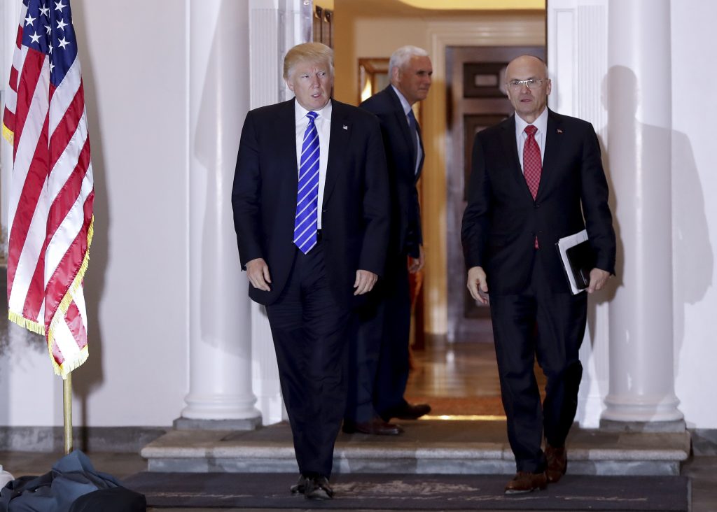 FILE - In this Nov. 19, 2016 file photo, President-elect Donald Trump walks with CKE Restaurants CEO Andy Puzder from Trump National Golf Club Bedminster clubhouse in Bedminster, N.J. Trump is expected to add another wealthy business person and elite donor to his Cabinet, with fast food executive Andrew Puzder as Labor secretary. In the background is Vice President-elect Mike Pence. (AP Photo/Carolyn Kaster)