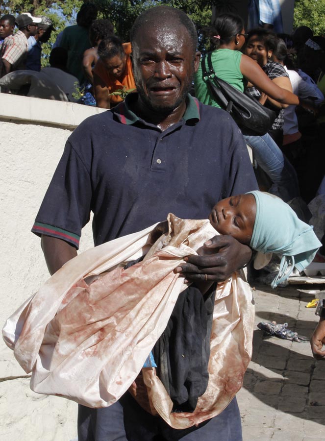 Ferido, haitiano carrega sua criança morta, vítima do terremoto. Porto Príncipe, Haiti, 13/01/2010. Foto: Eduardo Munoz/Reuters