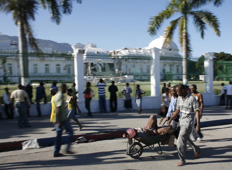 Homem carrega uma vítima do terremoto em um carrinho de mão, em frente ao palácio presidencial totalmente destruído. Porto Príncipe, Haiti. 13/01/2010. Foto: Eduardo Munoz/Reuters