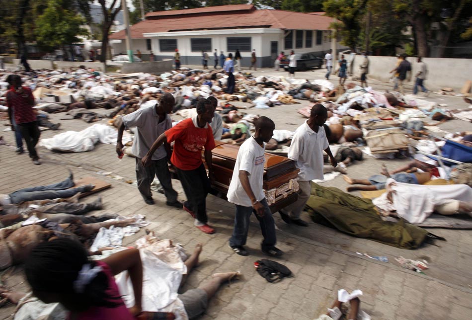 Haitianos carregam caixão, em meio a inúmeros corpos, próximo ao hospital geral. Porto Príncipe, Haiti. 13/01/2010. Foto: Eduardo Munoz/Reuters