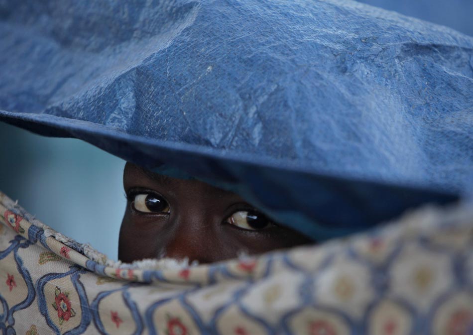 Um menino olha por entre uma fresta da tenda que serve como abrigo. Poto Príncipe, Haiti. 19/01/2010. Foto: Jae C. Hong/AP