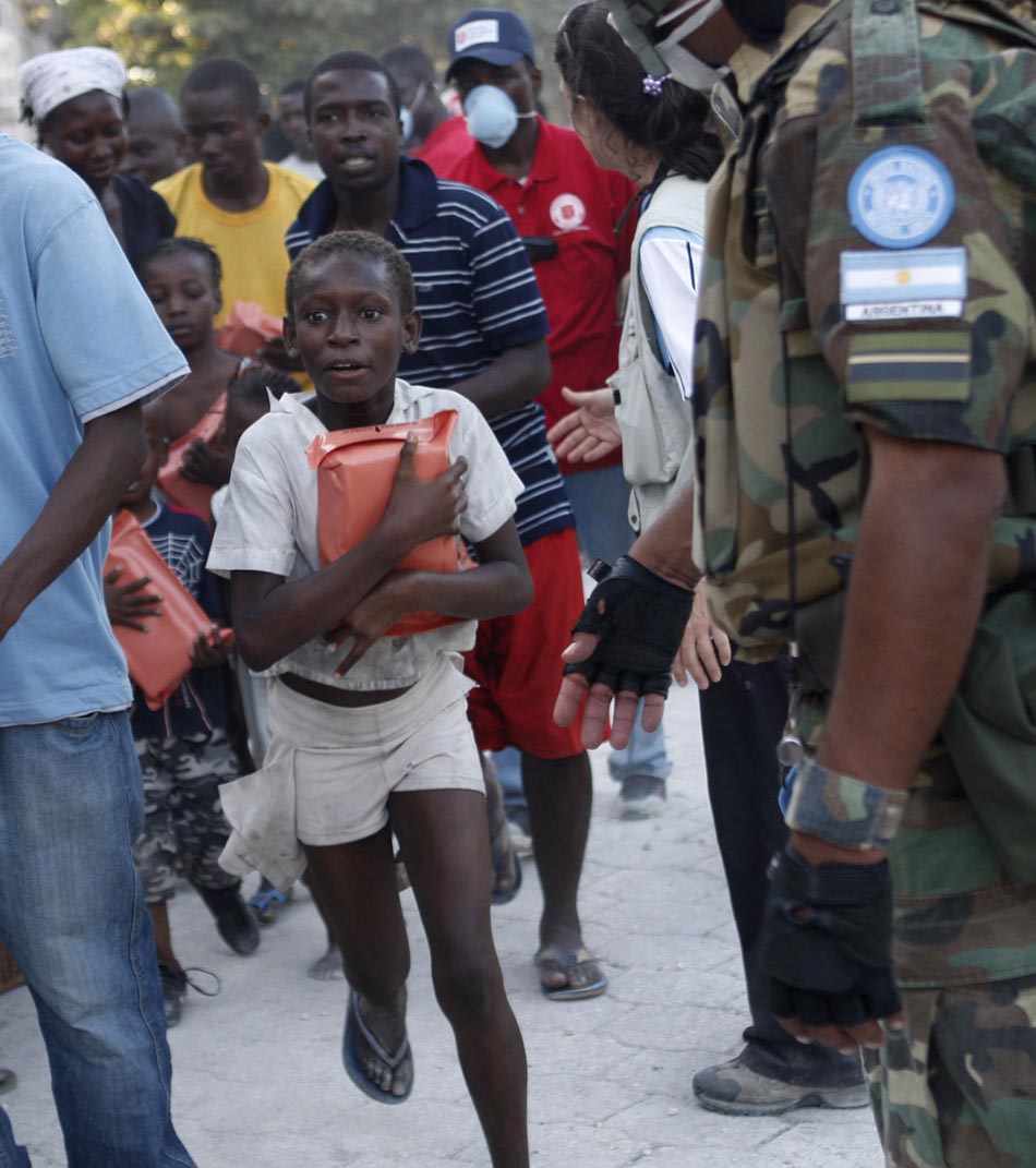 Uma criança corre em meio à população, após conseguir um pacote de alimento. Porto Príncipe, Haiti. 18/01/2010. Foto: Tatyana Makeyeva/Reuters