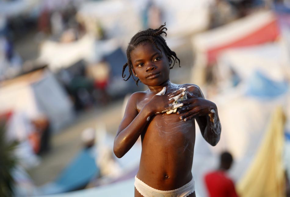 Uma menina toma banho em um campo de refugiados. Porto Príncipe, Haiti. 18/01/2010. Foto: Jorge Silva/Reuters