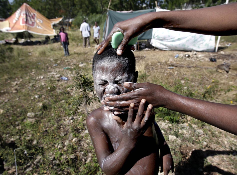 Rolgens Almondm de 5 anos, tem o rosto lavado pela mãe. Porto Príncipe, Haiti. 18/01/2010. Foto: Patrick Farrell/The Miami Herald/AP
