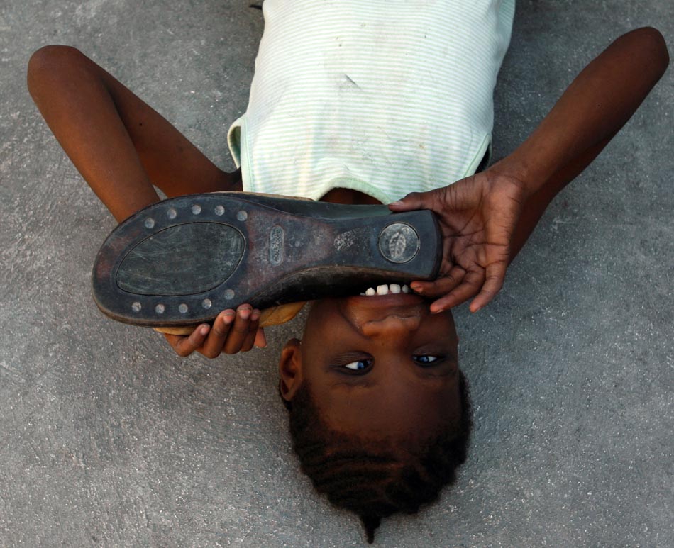 Menina brinca com o sapato. Porto Príncipe, Haiti. 18/01/2010. Foto: Carl Juste/The Miami Herald/AP
