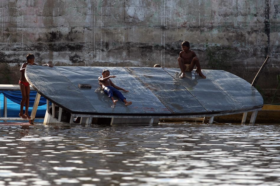 Crianças brincam em embarcação virada no Rio Xingu, próximo ao porto de Altamira. PA, 14/04/2010. FOTO: HÉLVIO ROMERO/AE