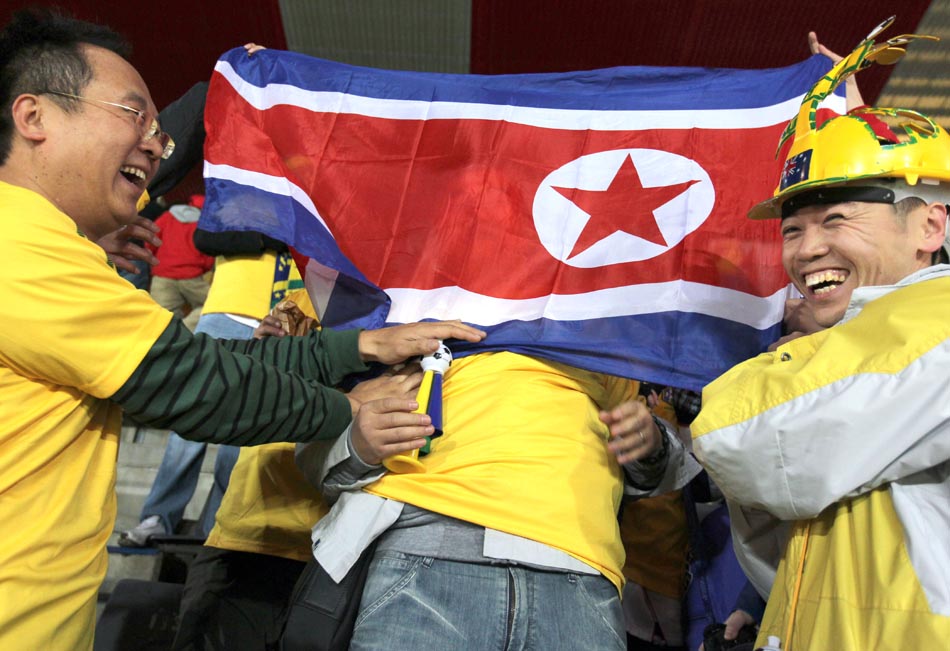 Torcedores seguram bandeira da Coreia do Norte, mesmo com roupas amarelas. Estádio Ellis Park, em Johanesburgo. 15/06/2010. Foto: Wilton Junior/AE