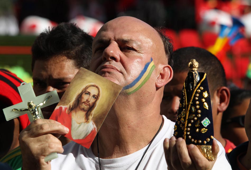 Torcedor segura imagens de santos no Vale do Anhangabaú, em São Paulo, para acompanhar o jogo de estreia da seleção. 15/06/2010. Foto: Epitácio Pessoa/AE