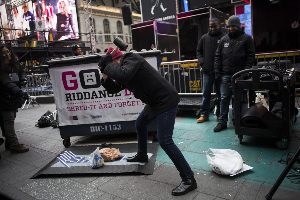 STANDALONE -- A participant smashes old memories using a rubber hammer during the Times Square New Year's Eve Good Riddance Day in Times Square in Manhattan, Dec. 28, 2016. The 10th annual event held in Times Square invites visitors to shred, discard and destroy bad memories from 2016 in a mobile shredding truck. (John Taggart/The New York Times)